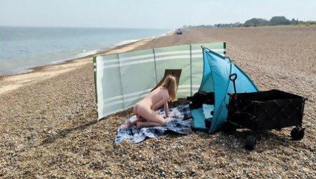 A young blonde wife is nude and masturbating on a British public beach